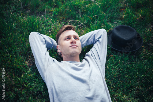 young man lying on grass hat near