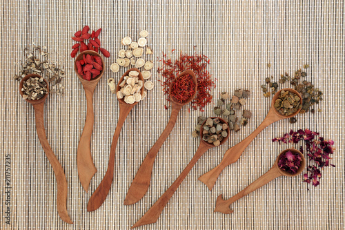 Chinese herbal medicine with herbs in wooden spoons on bamboo background. Top view.