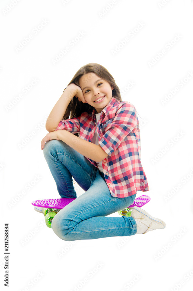 Happy child sit on penny board isolated on white. Little girl smile with beauty look. Carefree kid with skateboard. Casual fashion and style. Skateboarding is a fun Happy child sit on penny board isolated on white. Little girl smile with beauty look. Carefree kid with skateboard. Casual fashion and style. Skateboarding is a fun
