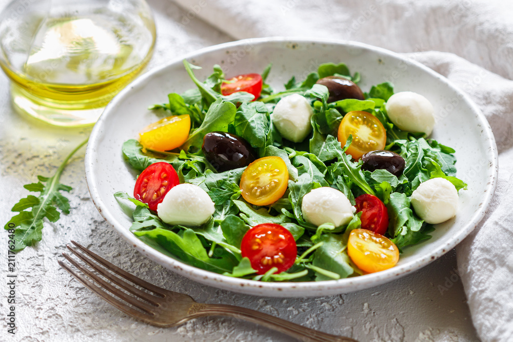 Fresh summer salad with arugula, yellow and red cherry tomatoes, Kalamata olives and mozzarella