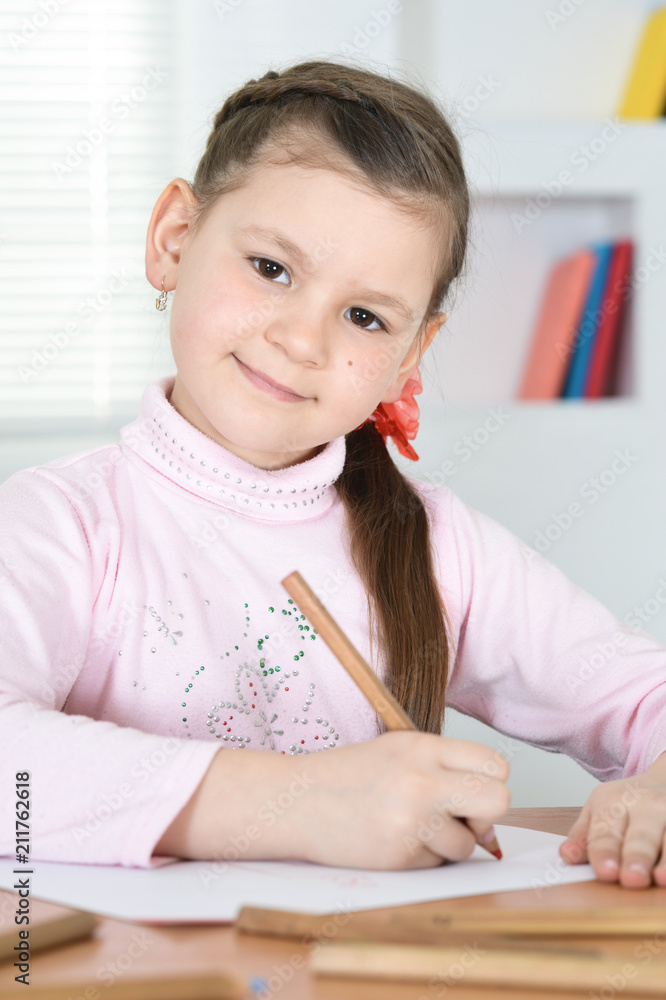 Cute schoolgirl sitting at table and drawing Cute schoolgirl sitting at table and drawing