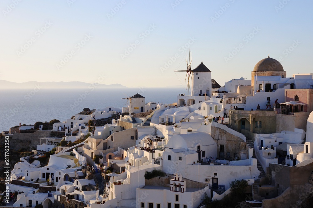 Famous stunning view of white architectures and windmills above the volcanic caldera in the village of Oia in Santorini island, Greece
