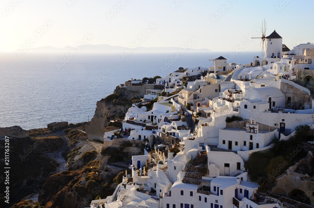 Famous stunning view of white architectures and windmills above the volcanic caldera in the village of Oia in Santorini island, Greece