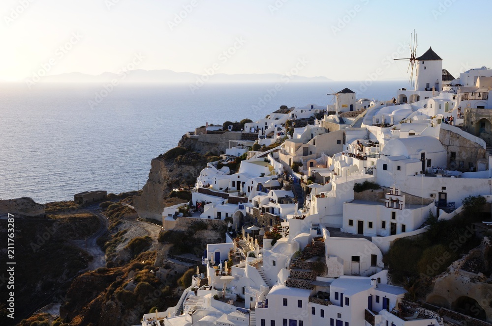 Fototapeta premium Famous stunning view of white architectures and windmills above the volcanic caldera in the village of Oia in Santorini island, Greece
