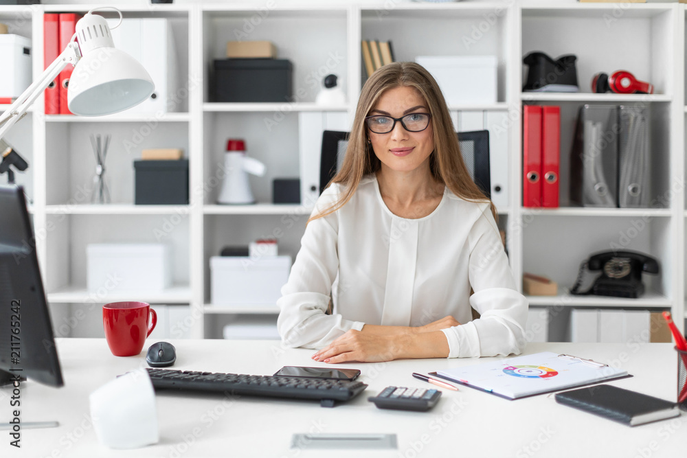A young girl is sitting at the computer desk in the office. A young girl is sitting at the computer desk in the office.