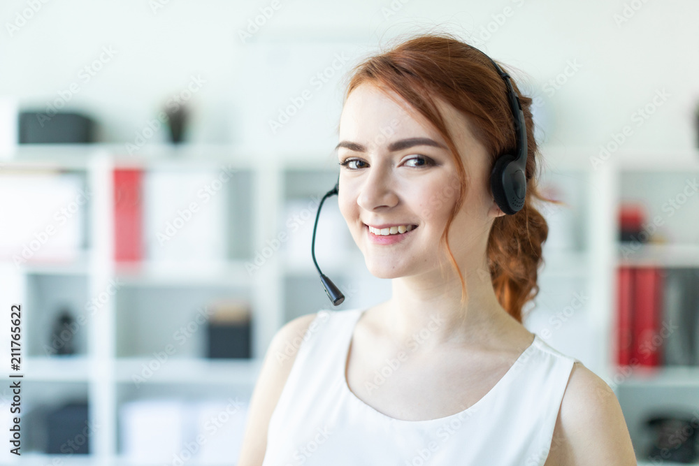 Naklejka premium Beautiful young girl in headphones with microphone standing in office.