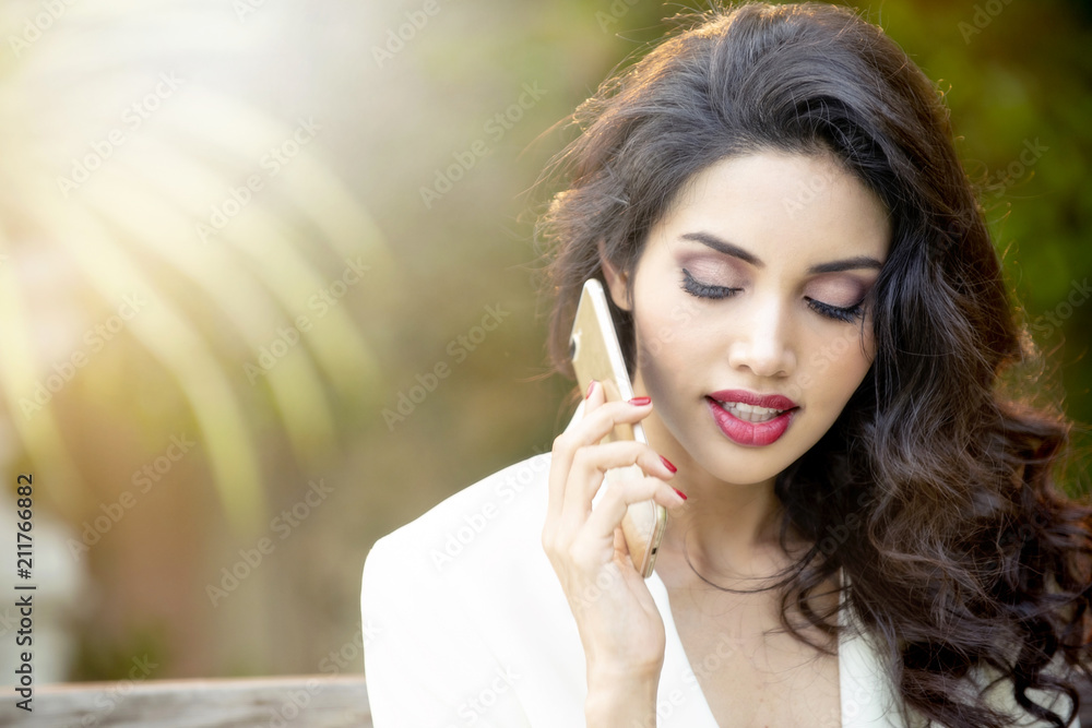 Charming stylish caucasian girl with shy smile using smart phone in summer