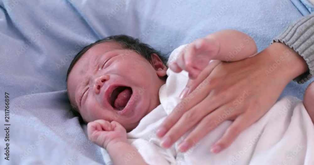 New born baby crying with hand comforting New born baby crying with hand comforting