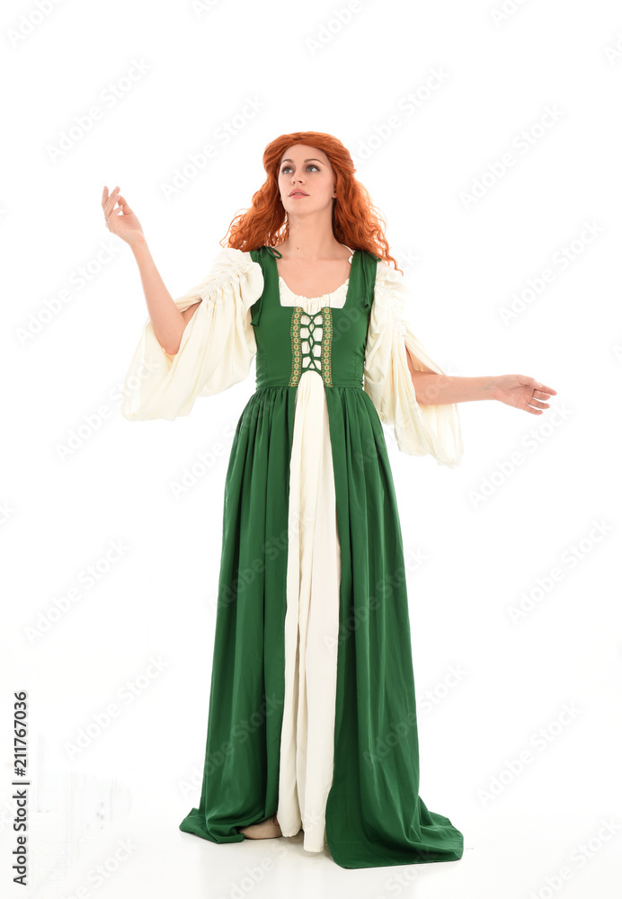 full length portrait of red haired girl wearing long green medieval gown. standing pose, isolated on white studio background.