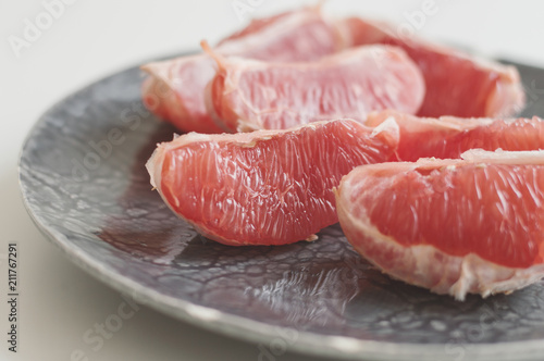 Grapefruit slices on gray plate, minimal photo, selective focus