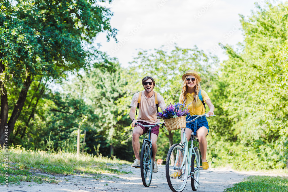 young couple riding retro bicycles in park on summer day young couple riding retro bicycles in park on summer day