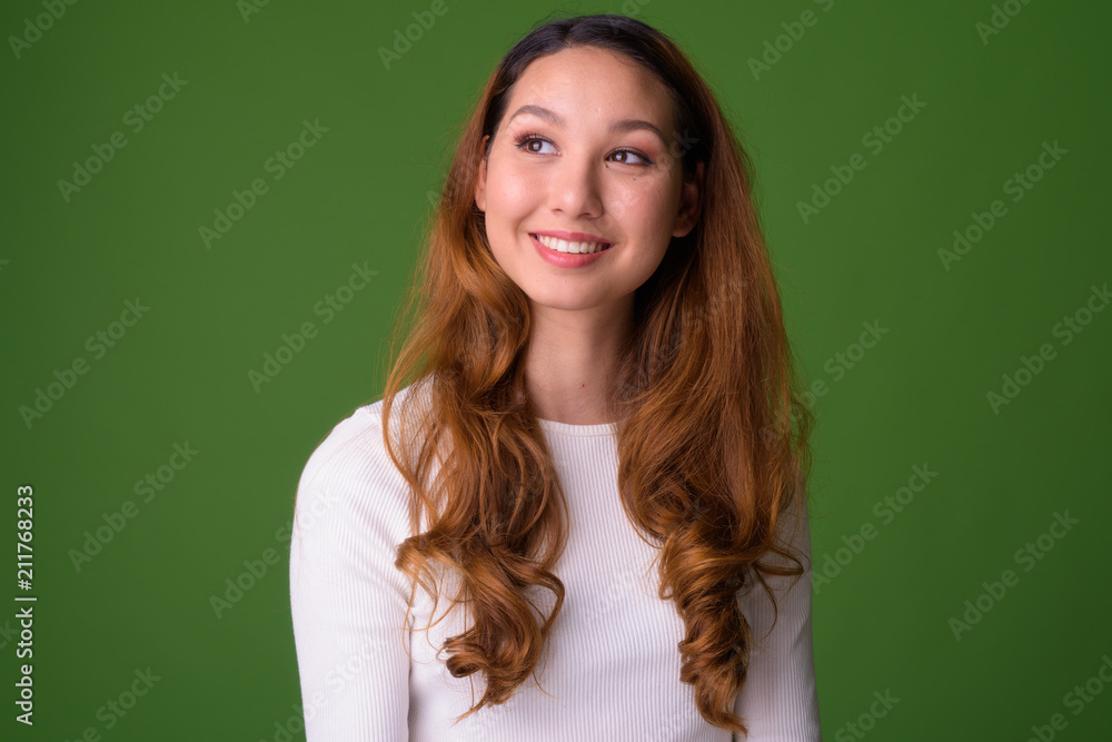 Young beautiful Asian woman against green background Young beautiful Asian woman against green background