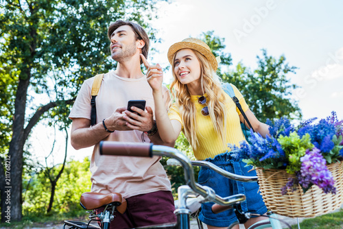 young couple with smartphone in park on summer day