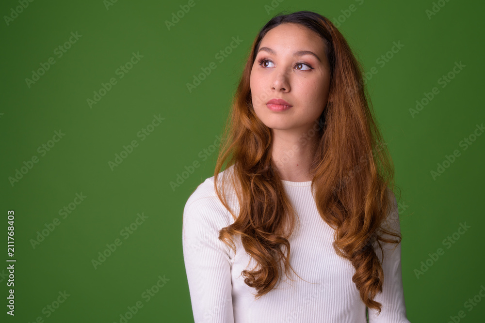 Young beautiful Asian woman against green background Young beautiful Asian woman against green background