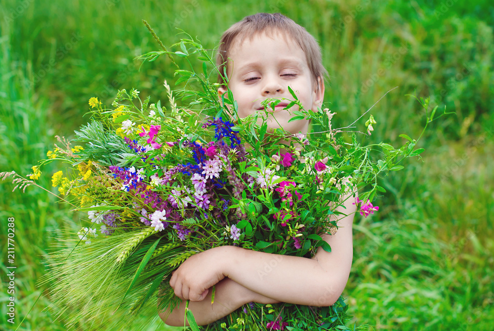 Happy child boy with bouquet of wild flowers in his hands enjoying by Summer Happy child boy with bouquet of wild flowers in his hands enjoying by Summer