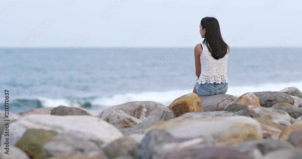 Woman sitting at seaside and looking at the sea Woman sitting at seaside and looking at the sea