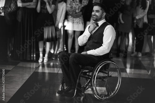 Handsome groom on the wheelchair waits for a bride in the center of dancing floor