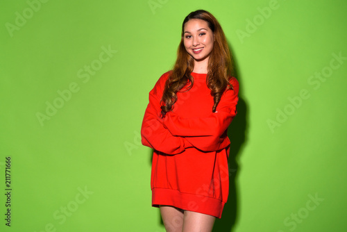 Young beautiful Asian woman against green background