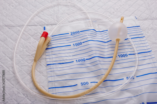 Nurse inflates urinary catheter bulb with leg drainage bag on sterile field. photo