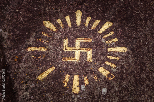 Fototapeta Swastika carved and drawn on a rock - an ancient solar hinduism symbol in the In