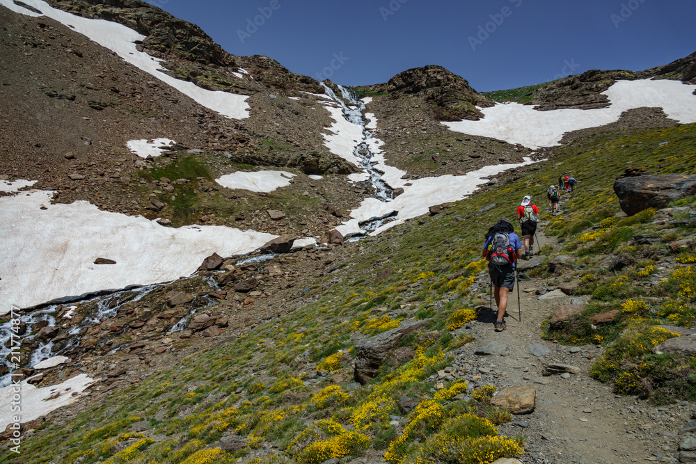 Hikers ascending mountain with waterfall Hikers ascending mountain with waterfall
