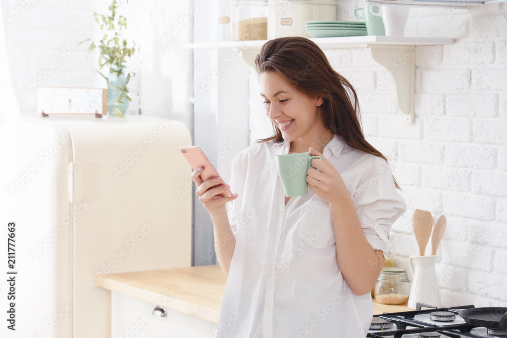 Young beautiful woman in the kitchen, drinking coffee and talking on the phone. Young beautiful woman in the kitchen, drinking coffee and talking on the phone.