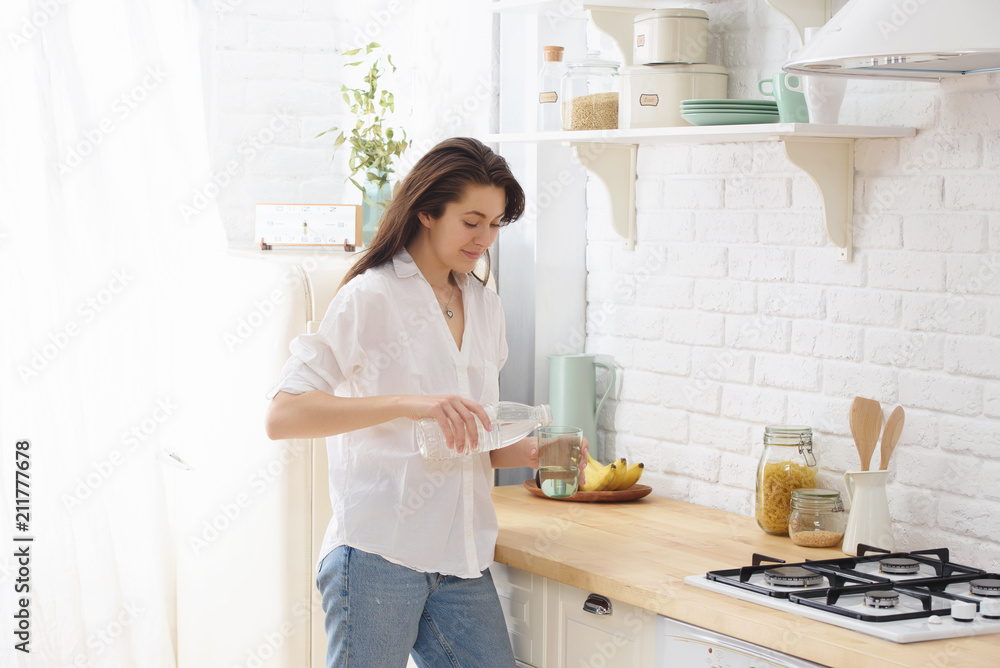 Young woman drinking water from glass in the kitchen Young woman drinking water from glass in the kitchen