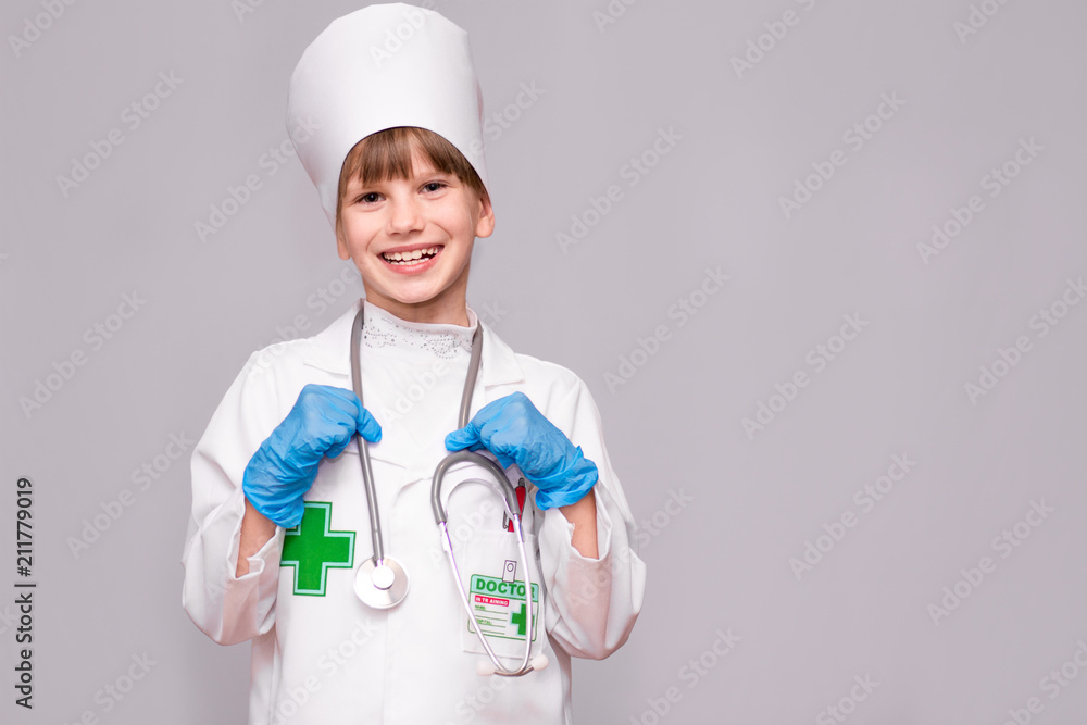 Smiling little girl in medical uniform holding stethoscope and looking at camera isolated on white