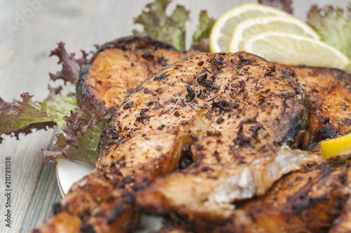 Fried salmon on a white plate decorated with lemon and salad