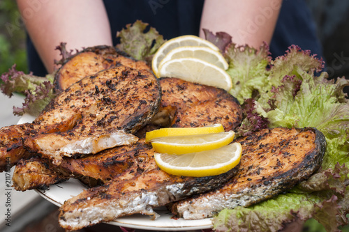 Fried salmon on a white plate decorated with lemon and salad