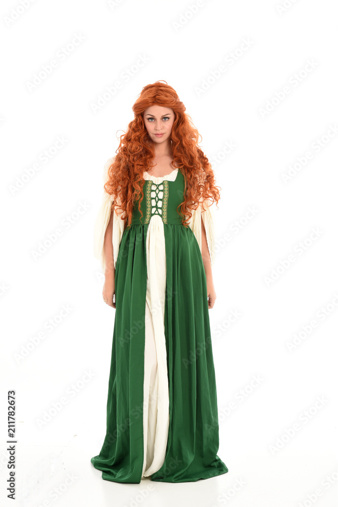 full length portrait of red haired girl wearing long green medieval gown. standing pose, isolated on white studio background. full length portrait of red haired girl wearing long green medieval gown. standing pose, isolated on white studio background.