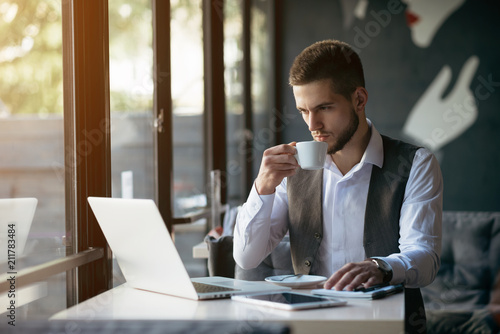 Young businessman working on a plan of Internet project on the laptop. Man discusses business matters by phone. Working computer for internet research. Digital marketing. Development