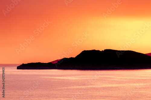 Warm summer sunset over the sea with clear sky in Montenegro with an island silhouette