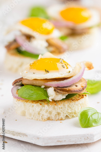 Canapes with fried mushrooms, quail egg, soft cheese and basil, beautiful appetizer for home party or event