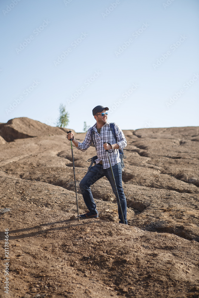 Image of happy tourist man with sticks for walking on hill