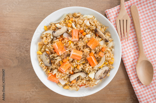 top view of fried rice with crab stick and vegetable in a ceramic dish on wooden table. asian homemade style food concept.