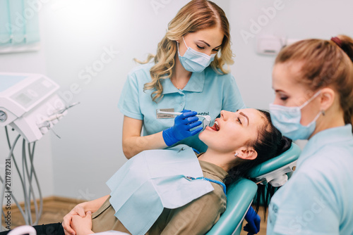 young woman dentist performs examination of patient in clinic