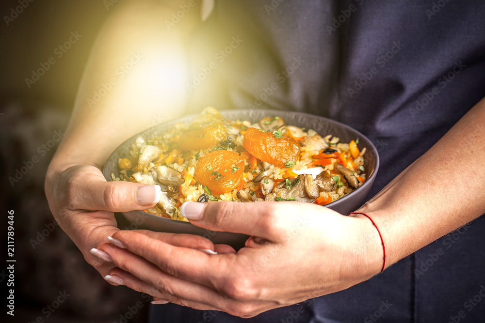 The girl cook holds a plate with a vegetarian plov, Uzbek traditional cuisine The girl cook holds a plate with a vegetarian plov, Uzbek traditional cuisine
