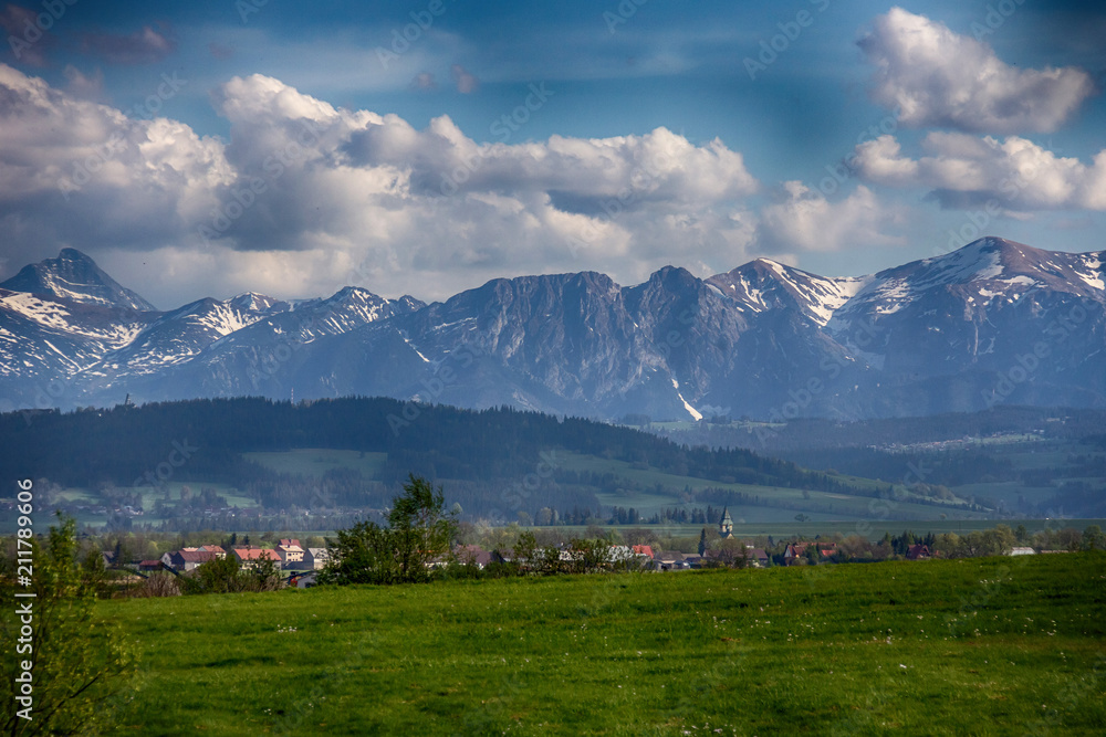 Rural buildings with a church tower on the background of the Tatra Mountains
