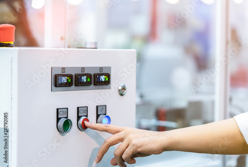 Engineer's hand push red button to shutdown temperature control machine. Temperature control panel cabinet contain digital screen display for temperature gauge. Heat control in industrial factory.