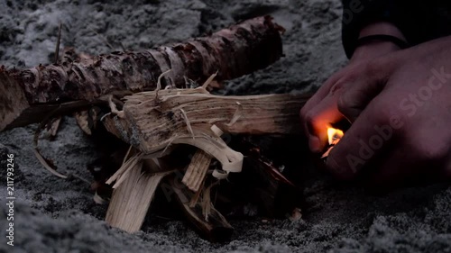 Person setting fire to wood to make a fireplace on sand photo