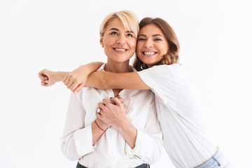 Portrait closeup of two attractive stylish women, young daughter hugging her beautiful mother, standing isolated over white background