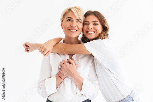 Portrait closeup of two attractive stylish women, young daughter hugging her beautiful mother, standing isolated over white background photo