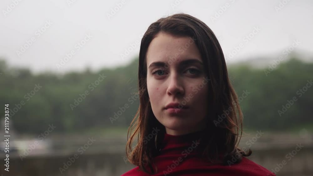Sad girl with wet hair looking at camera in rain, cloudy bad weather Sad girl with wet hair looking at camera in rain, cloudy bad weather