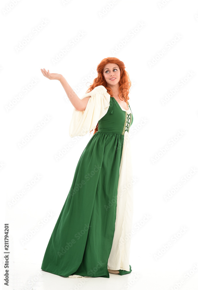 full length portrait of red haired girl wearing long green medieval gown. standing pose, isolated on white studio background.