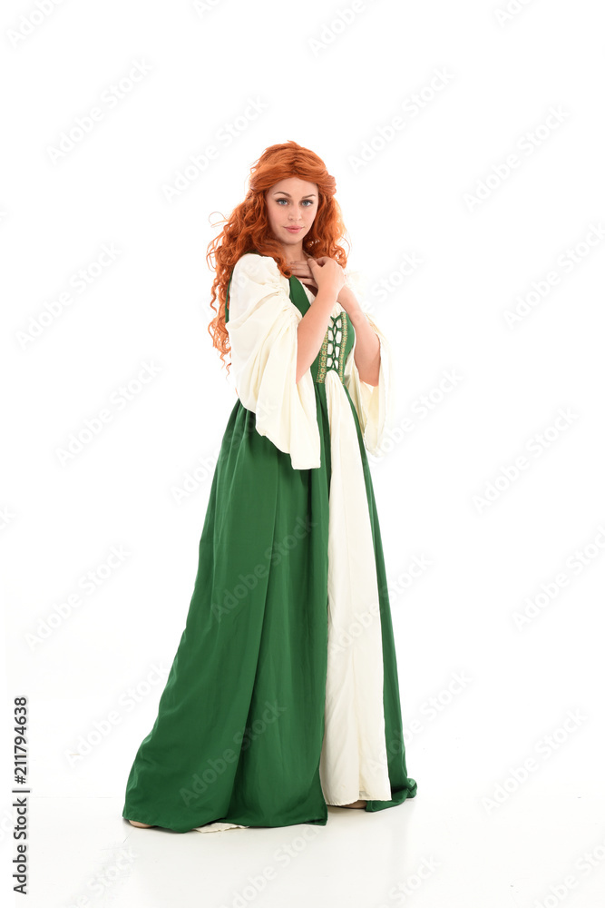 full length portrait of red haired girl wearing long green medieval gown. standing pose, isolated on white studio background.