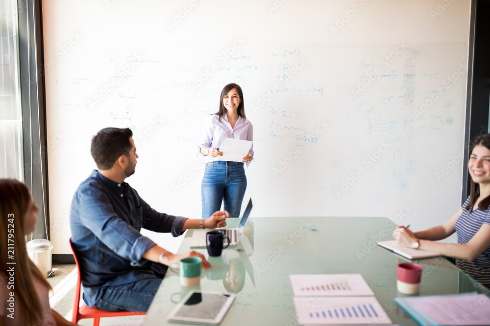 Obraz premium Smiling woman giving presentation to her team