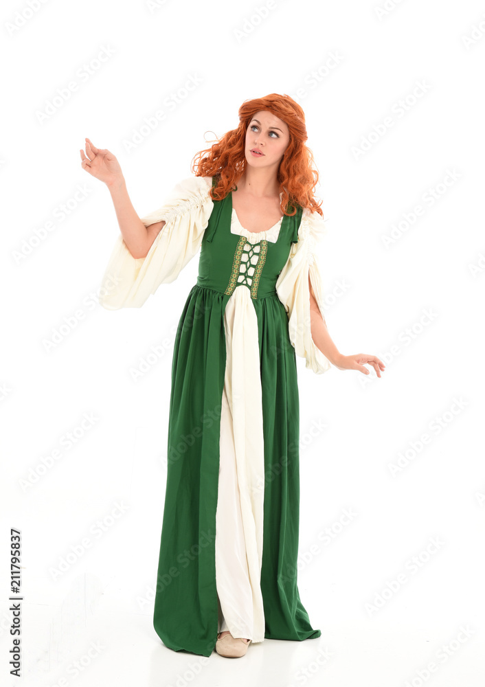 full length portrait of red haired girl wearing long green medieval gown. standing pose, isolated on white studio background. full length portrait of red haired girl wearing long green medieval gown. standing pose, isolated on white studio background.