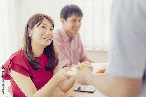 Asian waiters are serving food to couples with smiling.