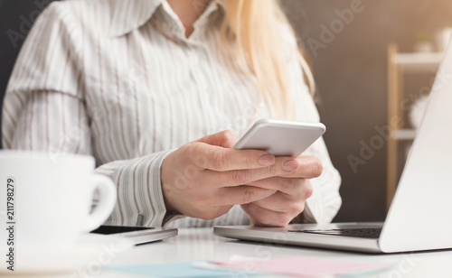 Woman manager holding smartphone at workplace